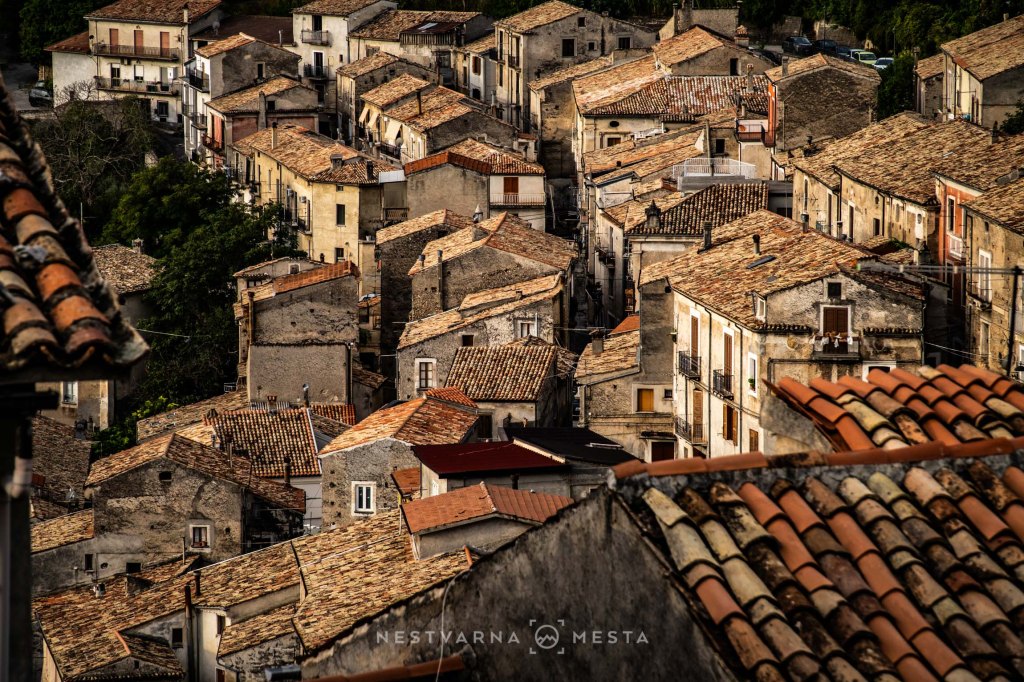 Aerial view of a historic town with narrow streets and closely packed buildings featuring tiled roofs.